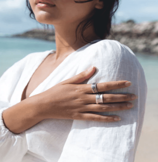 Devi Spinning Ring in luxurious sterling silver with flower-carved pattern and two spinning bands, displayed with complimentary tin