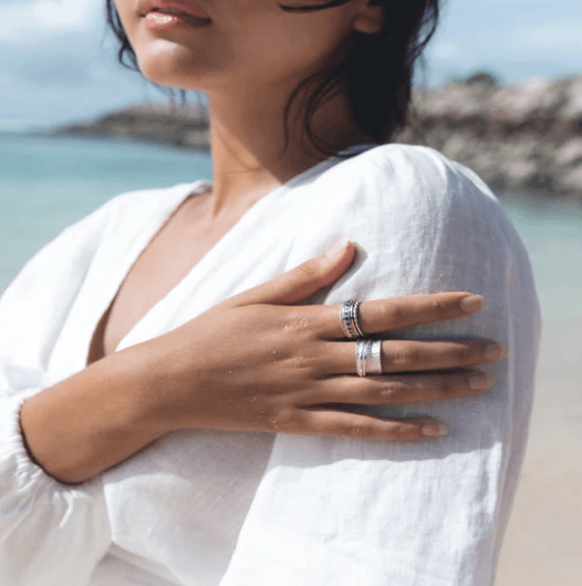 Garnet spinning ring with semi-precious gemstones, bordered by Rose Gold Spinning Bands, crafted in .925 Sterling Silver, displayed with complimentary MeditationRings Tin and Travel Pouch