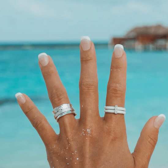 Sterling Silver Free-Floating Agoda Ring with white enamel spinning bands and CZ accent bar, displayed with complimentary MeditationRings Tin and Travel Pouch