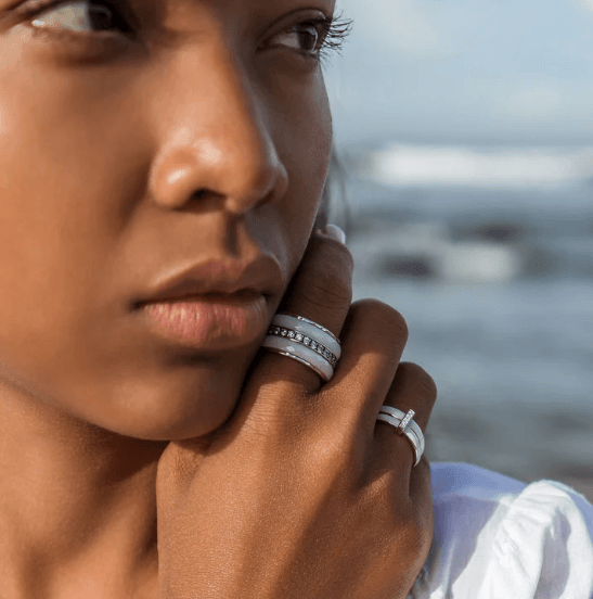 Sterling Silver Free-Floating Agoda Ring with white enamel spinning bands and CZ accent bar, displayed with complimentary MeditationRings Tin and Travel Pouch